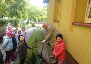 Nauczycielka z przedszkolakami sadzą drzewka